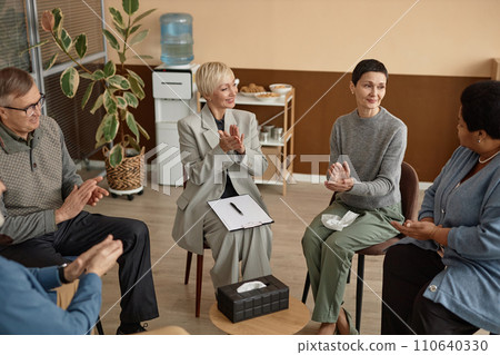 High angle view at adult people applauding in support group circle celebrating achievements together High angle view at adult people applauding in support group circle celebrating achievements together 110640330