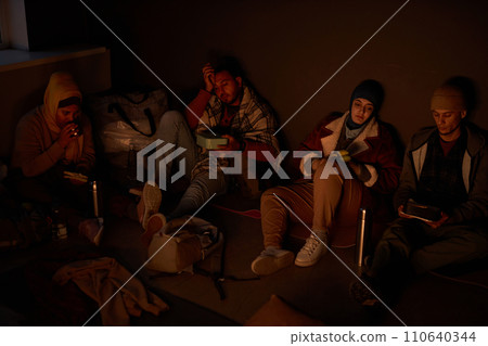 Diverse group of Middle Eastern people hiding in dark bomb shelter at night Diverse group of Middle Eastern people hiding in dark bomb shelter at night 110640344