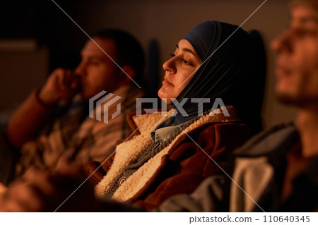 Diverse group of Middle Eastern people hiding in dark bomb shelter with young woman in foreground 110640345
