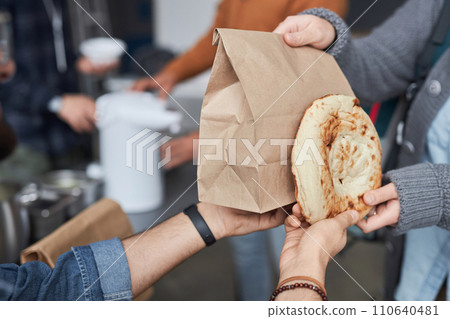 Close up of unrecognizable volunteer giving free food and bread to refugees at help center, copy space Close up of unrecognizable volunteer giving free food and bread to refugees at help center, copy space 110640481