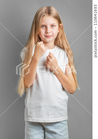 A little girl stands in a fighting pose. 110641693