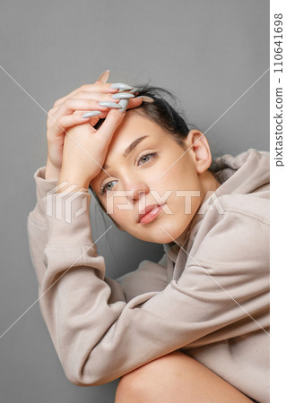 Pensive thoughtful young girl wearing sweatshirt with hood Pensive thoughtful young girl wearing sweatshirt with hood 110641698