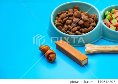 Dogs food in bowl and snacks on blue background 110642207