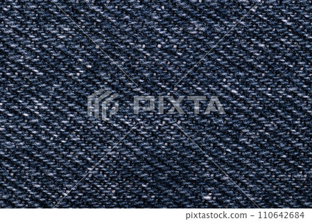 Denim surface, blue jeans fabric, front side, from above. Sturdy cotton warp-faced fabric. Type of textile weave with pattern of diagonal parallel ribs. Indigo dyed warp thread, and white weft thread. 110642684