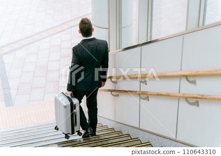 Foreign businessman descending the stairs with a suitcase Foreign businessman descending the stairs with a suitcase 110643310