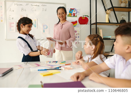 Smiling girl showing card with letter her classmates Smiling girl showing card with letter her classmates 110646805