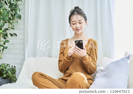 一位穿著家居服並操作智慧型手機的年輕女子 一位穿著家居服並操作智慧型手機的年輕女子 110647021