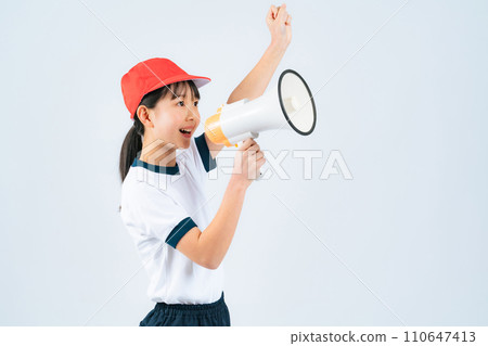 A girl wearing gym clothes cheering with a loudspeaker 110647413