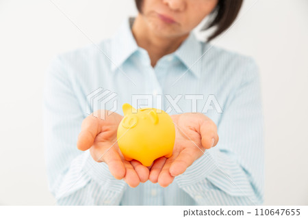 Hand of a worried middle-aged woman holding a piggy bank Hand of a worried middle-aged woman holding a piggy bank 110647655