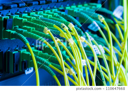 fiber optic cables plugged in network switch panel inside data center 110647668