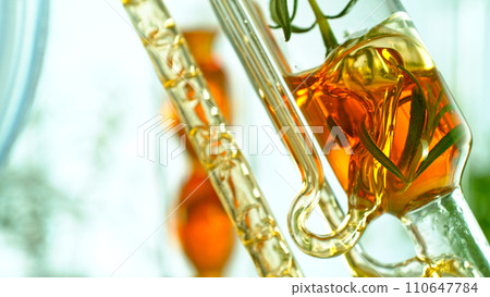 Getting natural oil from natural substances and flowers. Yellow oil flows in a spiral. Getting natural oil from natural substances and flowers. Yellow oil flows in a spiral. 110647784