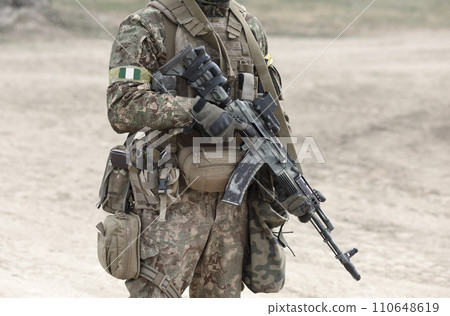 Soldier with machine gun and flag of Nigeria on military uniform. Collage. Soldier with machine gun and flag of Nigeria on military uniform. Collage. 110648619