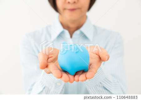 Middle-aged woman's hand holding a pig piggy bank 110648883