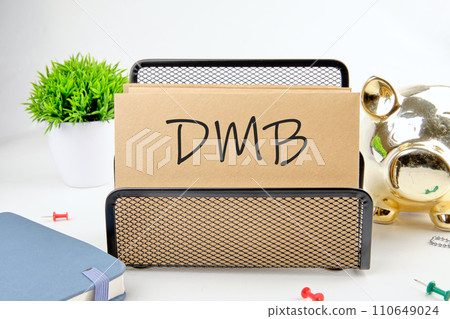 DMB text on paper next to piggy bank, notepad, flower on a white background DMB text on paper next to piggy bank, notepad, flower on a white background 110649024