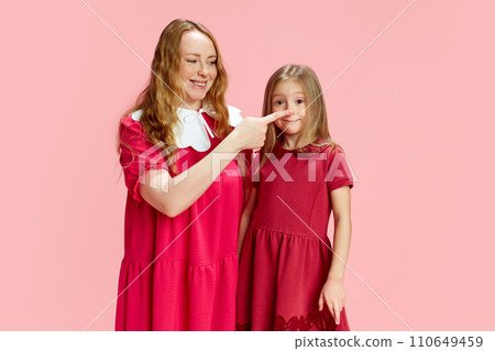 Playful parenting. Beautiful happy mother playing with her little Daubert against pink studio background. Fun and joy. Mother's Day, International Happiness Day Playful parenting. Beautiful happy mother playing with her little Daubert against pink studio background. Fun and joy. Mother's Day, International Happiness Day 110649459