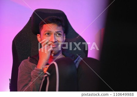 Handsome young man eating popcorn and watching a movie on computer at night. 110649988