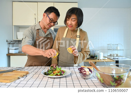 Middle age couple preparing healthy vegetables salad in kitchen. Happy senior lifestyle concept. Middle age couple preparing healthy vegetables salad in kitchen. Happy senior lifestyle concept. 110650007