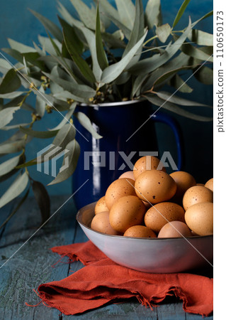 Still life with eggs in a bowl on a blue background 110650173