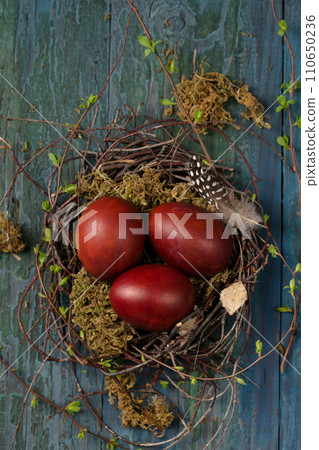 Easter eggs in a small nest made of branches and moss on a wooden background 110650236