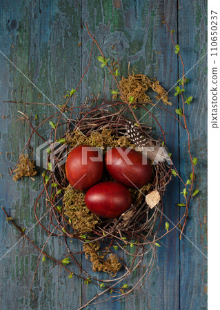 Easter eggs in a small nest made of branches and moss on a wooden background 110650237
