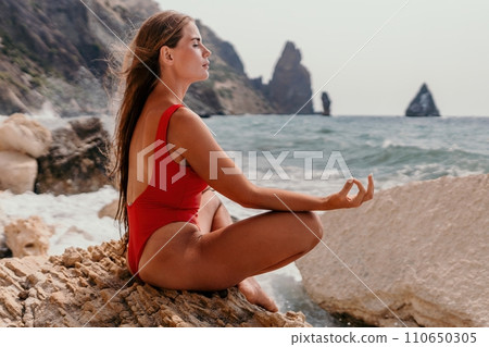 Woman sea yoga. Happy woman meditating in yoga pose on the beach, ocean and rock mountains. Motivation and inspirational fit and exercising. Healthy lifestyle outdoors in nature, fitness concept. Woman sea yoga. Happy woman meditating in yoga pose on the beach, ocean and rock mountains. Motivation and inspirational fit and exercising. Healthy lifestyle outdoors in nature, fitness concept. 110650305