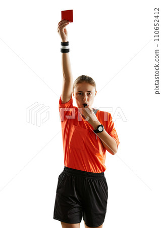 Young concentrated woman, soccer referee blowing a whistle and showing red card as dismissal symbol against white studio background Young concentrated woman, soccer referee blowing a whistle and showing red card as dismissal symbol against white studio background 110652412