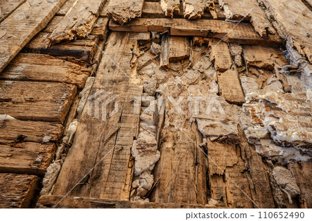 Old wooden wall damaged by termites. Close-up view. Rotten wall. Real photo. Low angle view 110652490