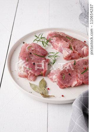 a piece of fresh raw pork meat with spices on a white wooden table. Meat with spices a piece of fresh raw pork meat with spices on a white wooden table. Meat with spices 110654287