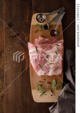 a piece of fresh raw pork meat with spices on a brown wooden table. Meat with spices a piece of fresh raw pork meat with spices on a brown wooden table. Meat with spices 110654312