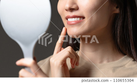 A woman checking her teeth in the mirror A woman checking her teeth in the mirror 110655304