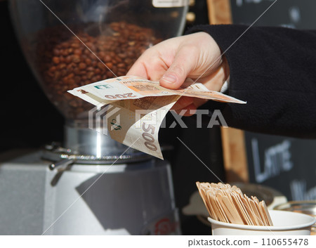 Womans hand paying for coffee with paper money Womans hand paying for coffee with paper money 110655478