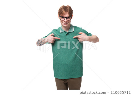 young caucasian male student with red hair and tattoo points with his hands at his green t-shirt young caucasian male student with red hair and tattoo points with his hands at his green t-shirt 110655711
