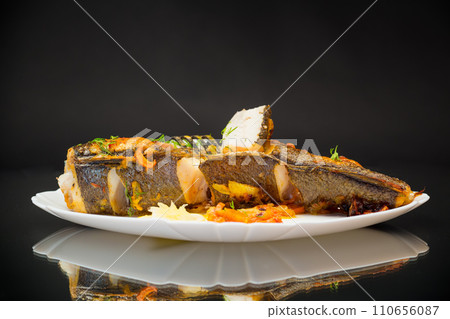 fish baked with spices and vegetables in the oven. 110656087