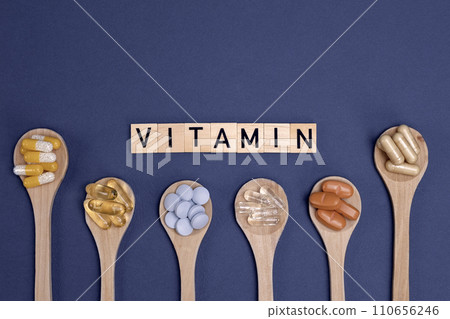 Different vitamins in wooden spoons with text on gray background Different vitamins in wooden spoons with text on gray background 110656246