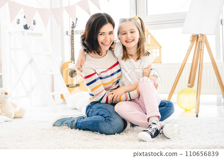 Smiling woman with little girl sitting on floor at home 110656839