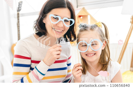 Portrait of smiling mother and daughter with stick glasses Portrait of smiling mother and daughter with stick glasses 110656840