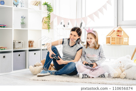 Happy mother and daughter playing video game in children room Happy mother and daughter playing video game in children room 110656874