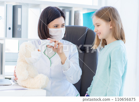 Smiling little girl and kind doctor measuring tempertaure of teddy bear Smiling little girl and kind doctor measuring tempertaure of teddy bear 110656875