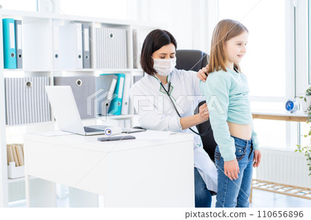 Nice doctor listening to little girl with phonendoscope 110656896