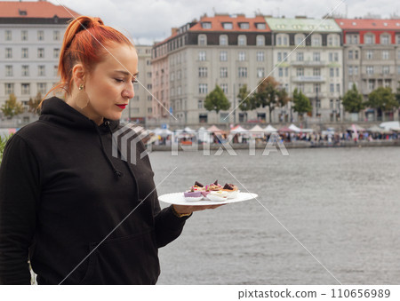 Pretty young woman, model, stallholder posing with tasty desserts 110656989