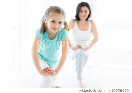 Cute little girl with trainer doing lunges in gym Cute little girl with trainer doing lunges in gym 110656993