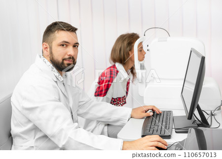 Teenage girl udergoes eye survey with doctor ophthalmologist on tomograph in clinic Teenage girl udergoes eye survey with doctor ophthalmologist on tomograph in clinic 110657013