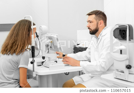 doctor examines a girl eyesight in a clinic 110657015