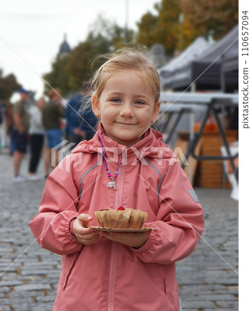 Cute baby girl posing with dessert at farmers market. Cute baby girl posing with dessert at farmers market. 110657094