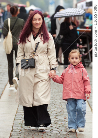 Smiling pretty young woman walking with her little daughter. 110657096