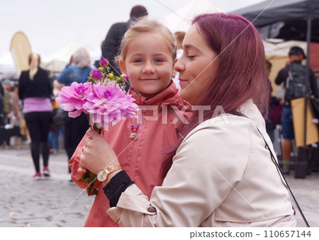 Young moman with little daughter buying fresh flower at market 110657144