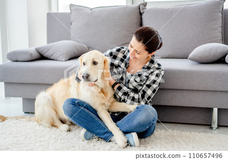 Happy woman petting cute dog in light apartment 110657496