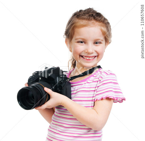 Pretty smiling little girl holding professional camera with big lens isolated on the white background Pretty smiling little girl holding professional camera with big lens isolated on the white background 110657608