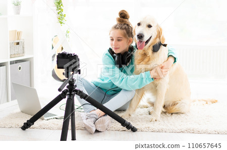 Cute teenage Blogger girl with nice dog in front of camera indoors 110657645