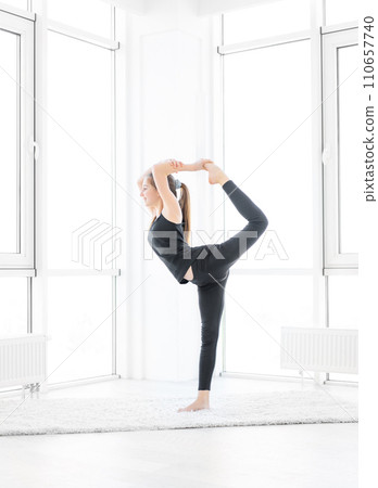 Pretty girl performing king dancer yoga asana indoors 110657740